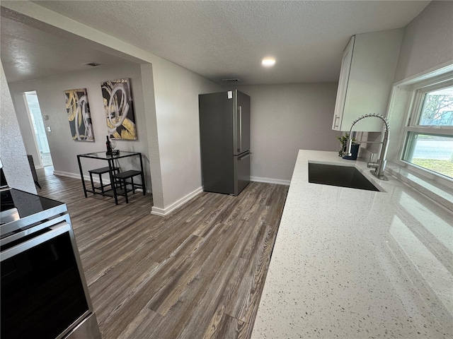 kitchen with sink, white cabinetry, stainless steel appliances, a textured ceiling, and dark hardwood / wood-style flooring