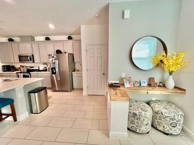 kitchen featuring appliances with stainless steel finishes, light tile patterned floors, backsplash, and butcher block countertops