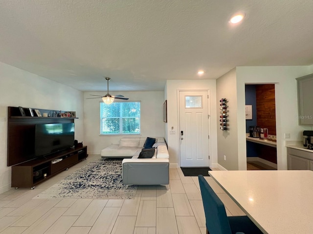 living room with ceiling fan and a textured ceiling