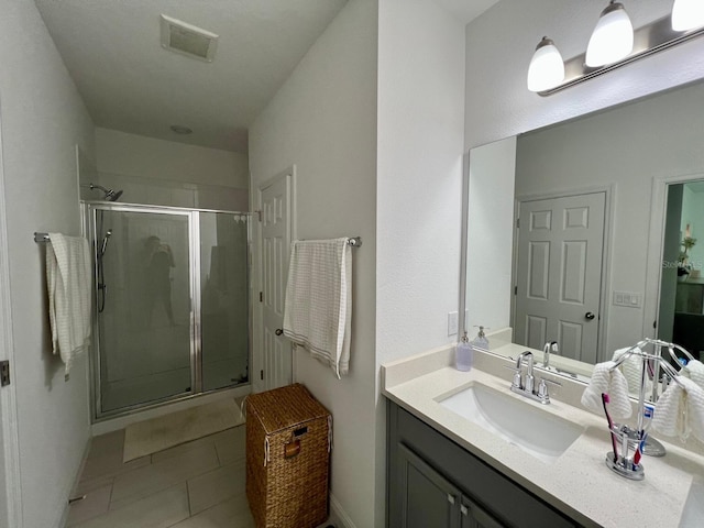 bathroom featuring vanity, a shower with shower door, and tile patterned flooring