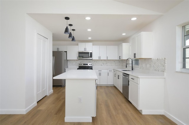 kitchen with hanging light fixtures, stainless steel appliances, sink, a center island, and white cabinets