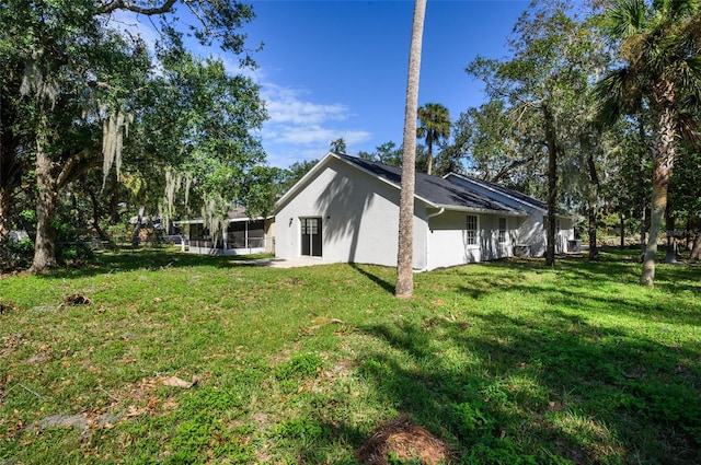 view of home's exterior with a sunroom and a lawn