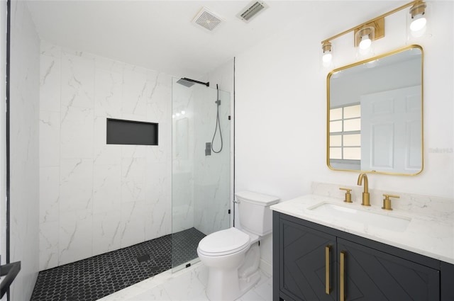 bathroom with vanity, tiled shower, and toilet