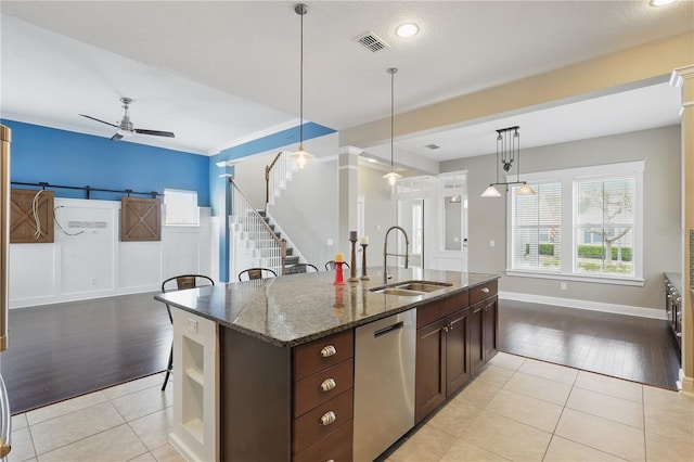 kitchen featuring dark brown cabinetry, dark stone counters, a sink, visible vents, and dishwasher