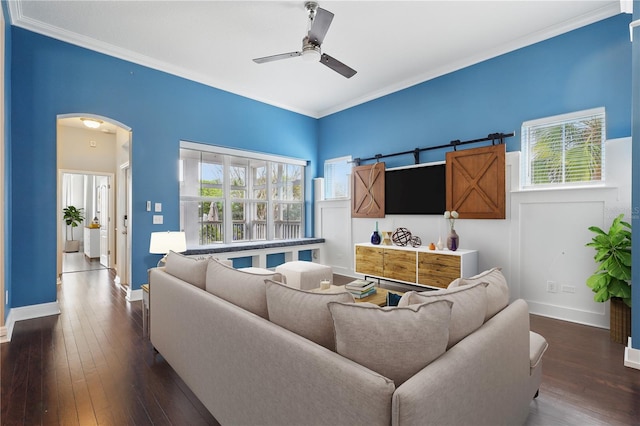 living area featuring ornamental molding, arched walkways, dark wood-style flooring, and a ceiling fan