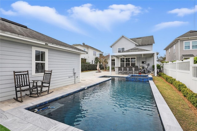 back of property featuring a fenced backyard, a pool with connected hot tub, and a patio