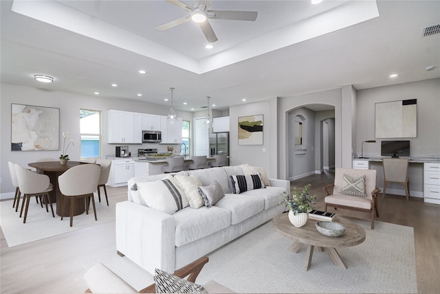 living room featuring ceiling fan, light hardwood / wood-style flooring, and sink