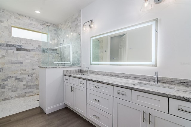 bathroom featuring a tile shower, vanity, and wood-type flooring