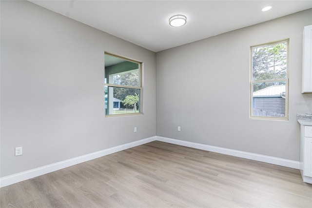 empty room with plenty of natural light and light hardwood / wood-style flooring