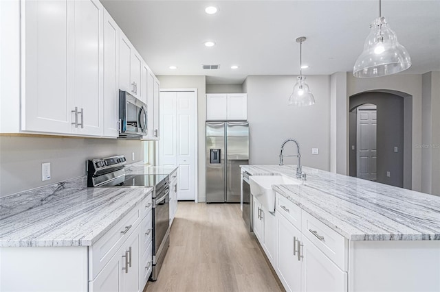 kitchen featuring stainless steel appliances, sink, light hardwood / wood-style flooring, white cabinets, and hanging light fixtures