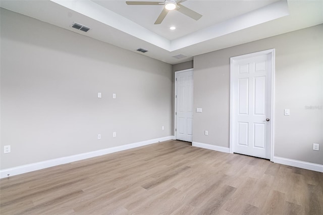 spare room featuring ceiling fan, a raised ceiling, and light hardwood / wood-style flooring