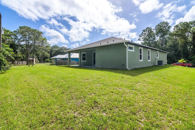 back of property with a yard and central AC