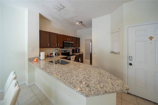 kitchen featuring kitchen peninsula, light stone counters, appliances with stainless steel finishes, a textured ceiling, and sink