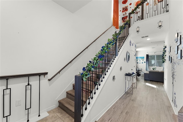 staircase featuring hardwood / wood-style floors and a towering ceiling