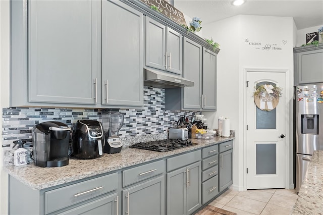 kitchen with appliances with stainless steel finishes, light stone counters, gray cabinetry, and light tile patterned flooring