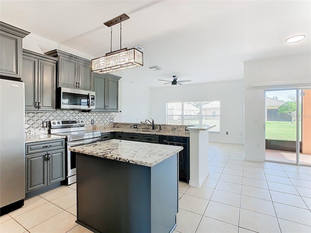 3623 Weatherfield Dr, Kissimmee, FL 34746 - kitchen with a peninsula, a center island, gray cabinets, backsplash, and stainless steel appliances