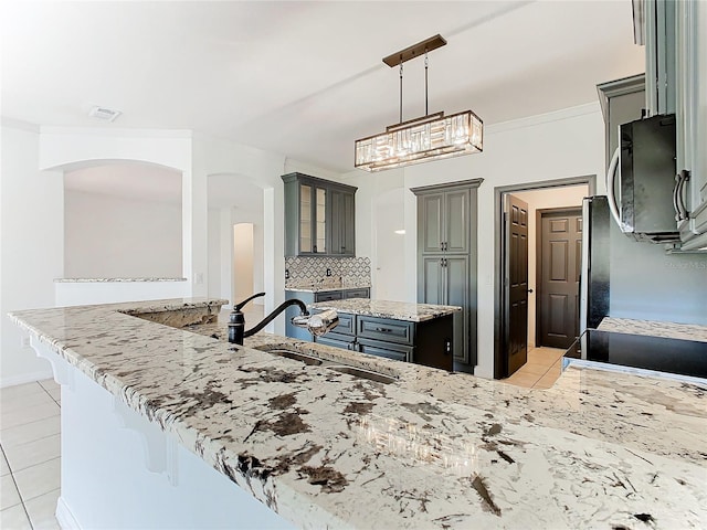 kitchen with gray cabinetry, sink, kitchen peninsula, a kitchen breakfast bar, and hanging light fixtures