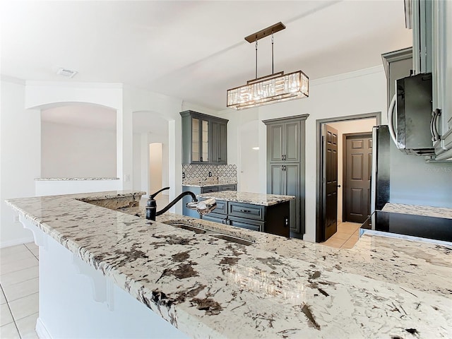 3623 Weatherfield Dr, Kissimmee, FL 34746 - kitchen with gray cabinets, light tile patterned floors, light stone counters, a sink, and stainless steel microwave