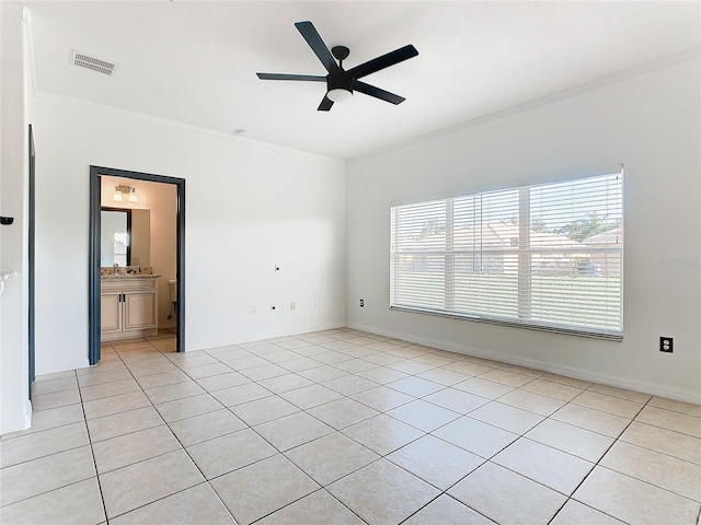 tiled empty room featuring ceiling fan and crown molding