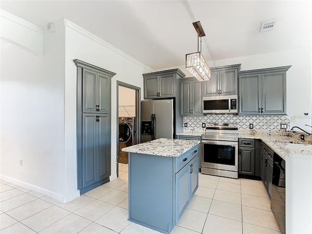 kitchen with appliances with stainless steel finishes, light tile patterned flooring, sink, a center island, and decorative light fixtures