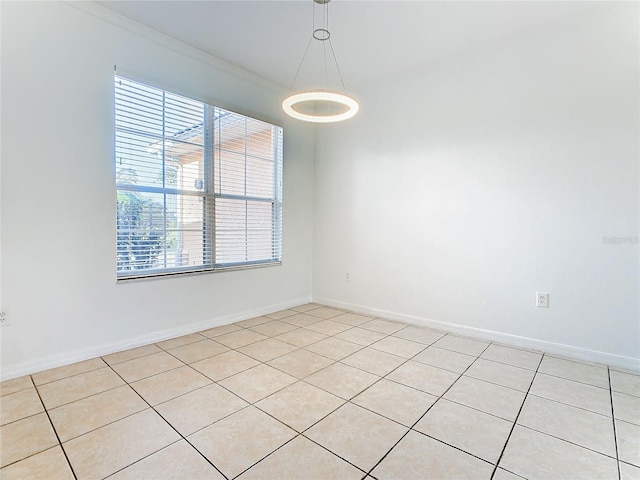 tiled spare room with ornamental molding and a healthy amount of sunlight