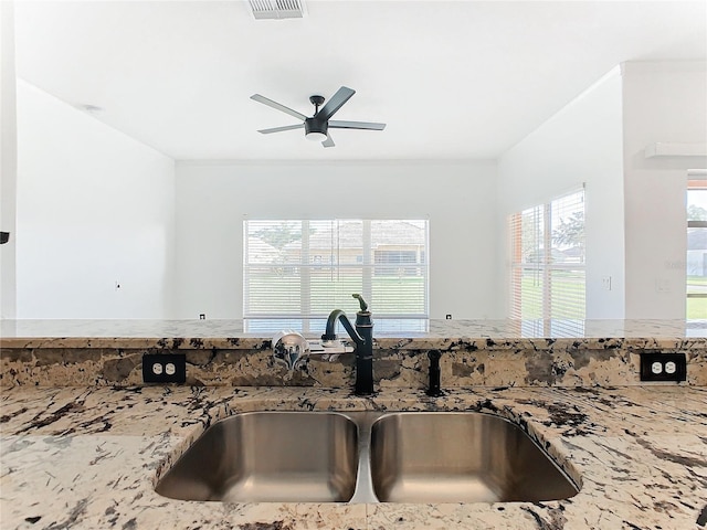 kitchen with sink, stone counters, and ceiling fan