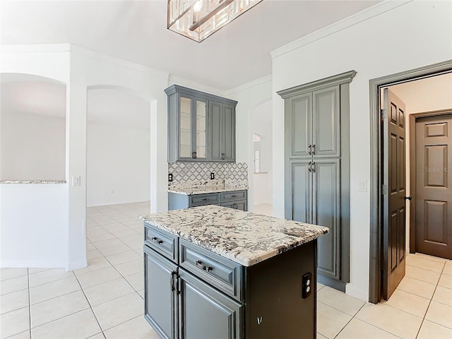 kitchen with a kitchen island, decorative backsplash, ornamental molding, light tile patterned floors, and gray cabinets