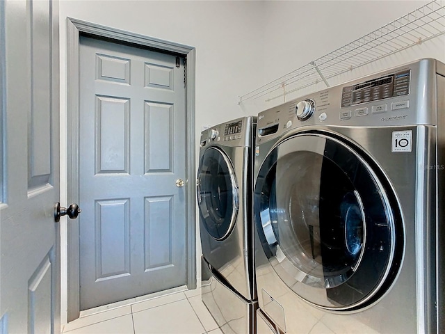 clothes washing area featuring washing machine and dryer and light tile patterned floors