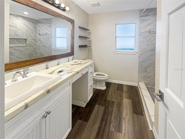 bathroom featuring a wealth of natural light, vanity, hardwood / wood-style floors, and a tile shower