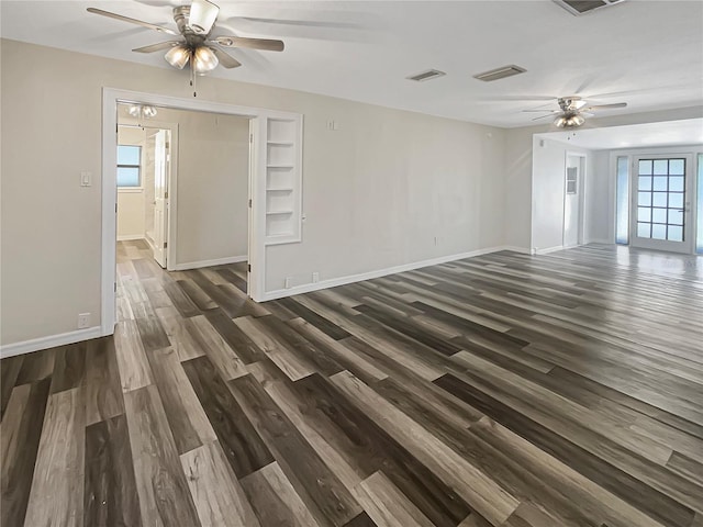 empty room with dark hardwood / wood-style floors, built in features, and ceiling fan