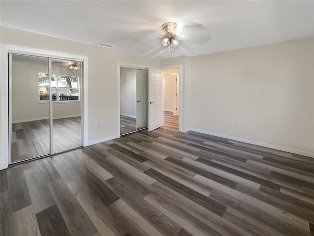 unfurnished bedroom featuring ceiling fan, a textured ceiling, and dark hardwood / wood-style flooring