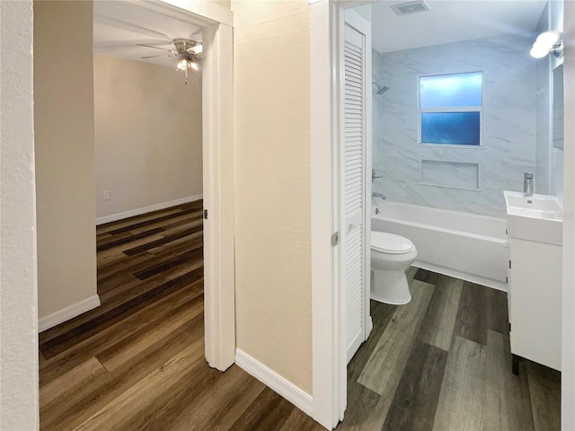 full bathroom featuring toilet, wood-type flooring, tiled shower / bath, vanity, and ceiling fan