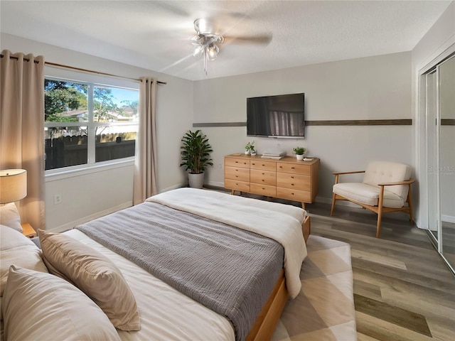 bedroom featuring light hardwood / wood-style flooring, a textured ceiling, a closet, and ceiling fan