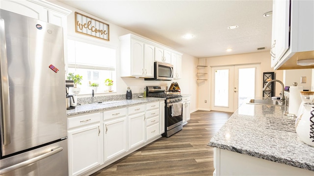 kitchen with dark hardwood / wood-style floors, light stone counters, white cabinetry, and stainless steel appliances