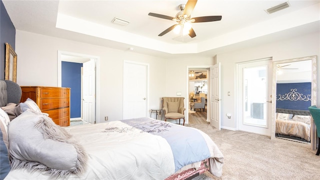 carpeted bedroom featuring ceiling fan and a tray ceiling