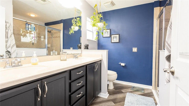 bathroom with hardwood / wood-style floors, vanity, a shower with door, and toilet