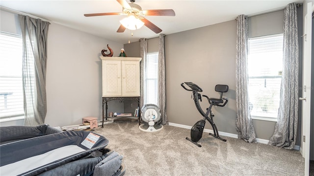 workout area featuring ceiling fan, a healthy amount of sunlight, and light colored carpet