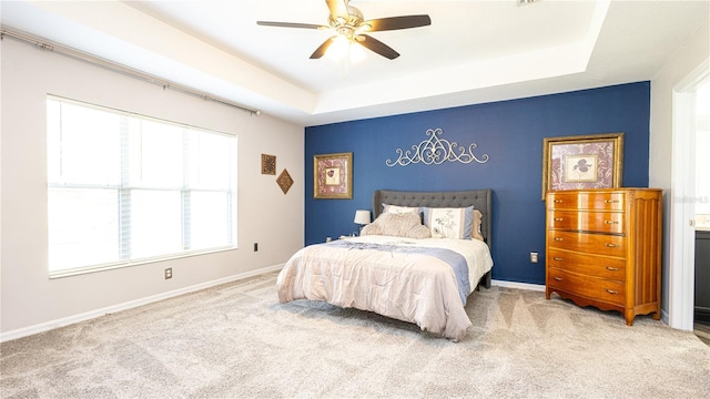 bedroom with light carpet, a raised ceiling, and ceiling fan