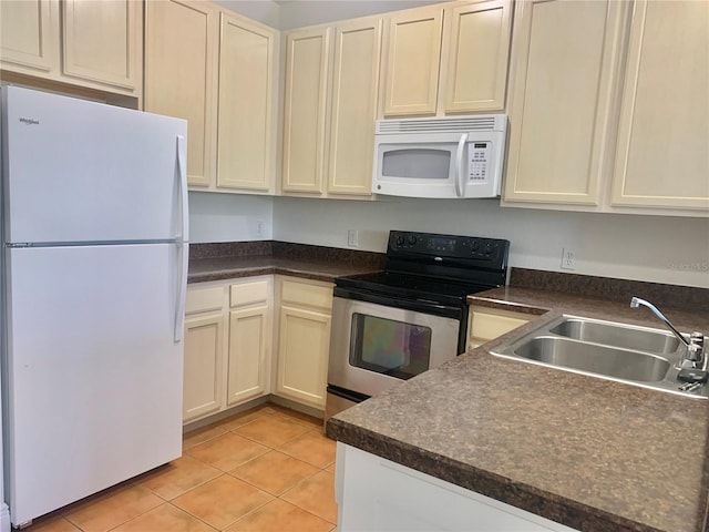 kitchen with cream cabinets, sink, light tile patterned floors, and white appliances