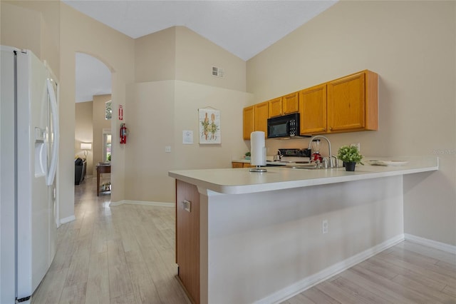 kitchen with kitchen peninsula, sink, white refrigerator with ice dispenser, and light wood-type flooring