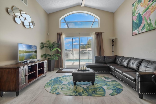 living room featuring light hardwood / wood-style floors, a textured ceiling, beam ceiling, and high vaulted ceiling