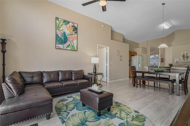 living room featuring lofted ceiling, light wood-type flooring, and ceiling fan