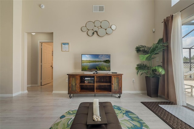 unfurnished living room with a towering ceiling and light wood-type flooring