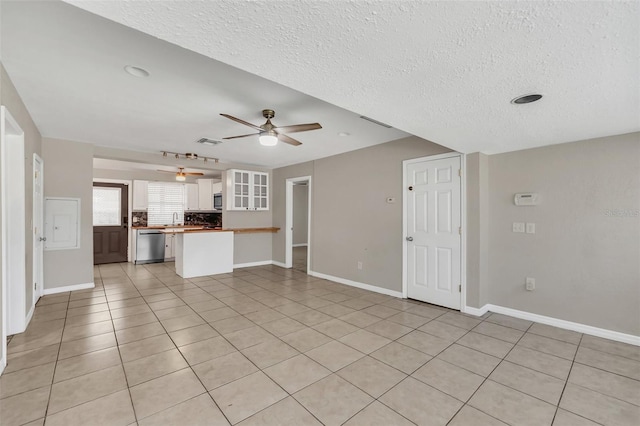 unfurnished living room featuring sink, ceiling fan, a textured ceiling, and light tile patterned floors