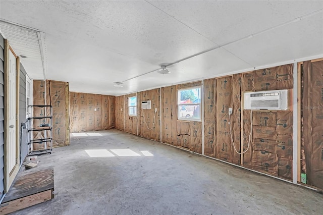 spare room with a wall unit AC, concrete floors, and wood walls