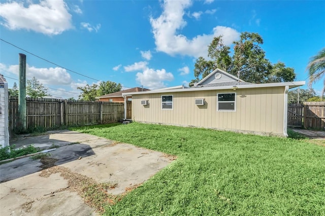 rear view of property with a patio area, a yard, and an AC wall unit