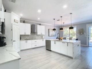 kitchen with a center island with sink, backsplash, decorative light fixtures, white cabinets, and dishwasher