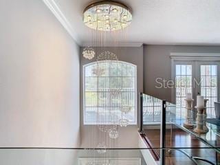 entrance foyer with a chandelier, french doors, and ornamental molding