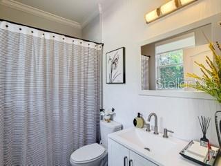 bathroom featuring toilet, vanity, ornamental molding, and curtained shower