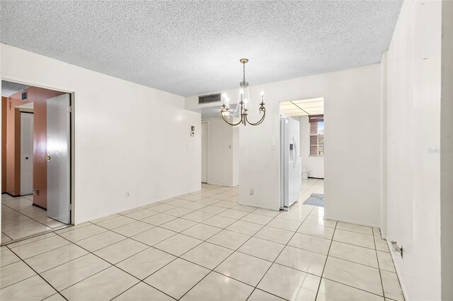 unfurnished dining area with an inviting chandelier, a textured ceiling, and light tile patterned floors